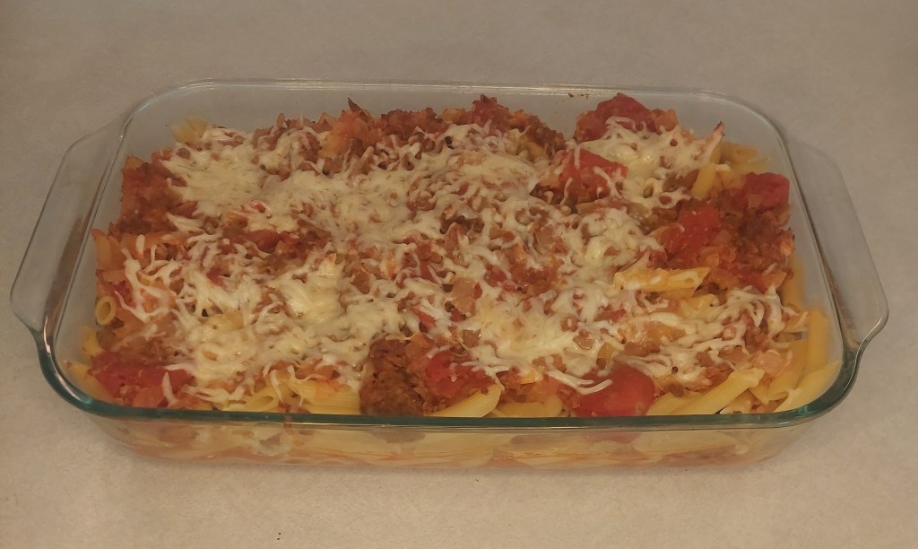 A picture of cooked pasta with sausage and tomatoes in a glass dish